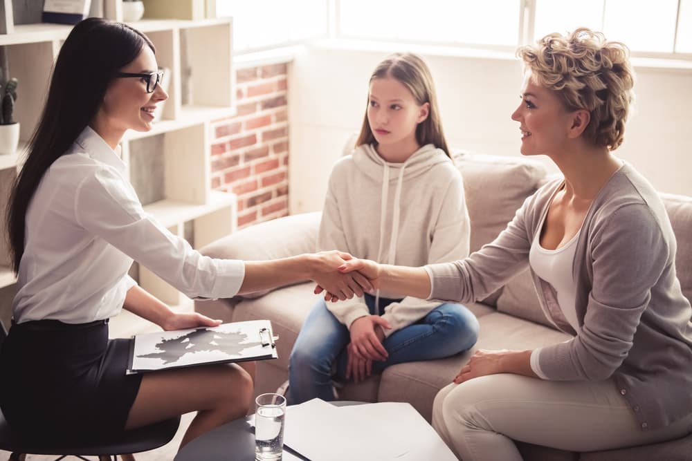 a mother meeting a therapist with her daughter for family counselling